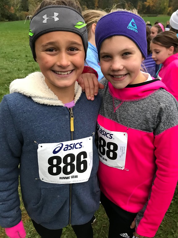 Two runners posing with race bib number visible on outside of coat